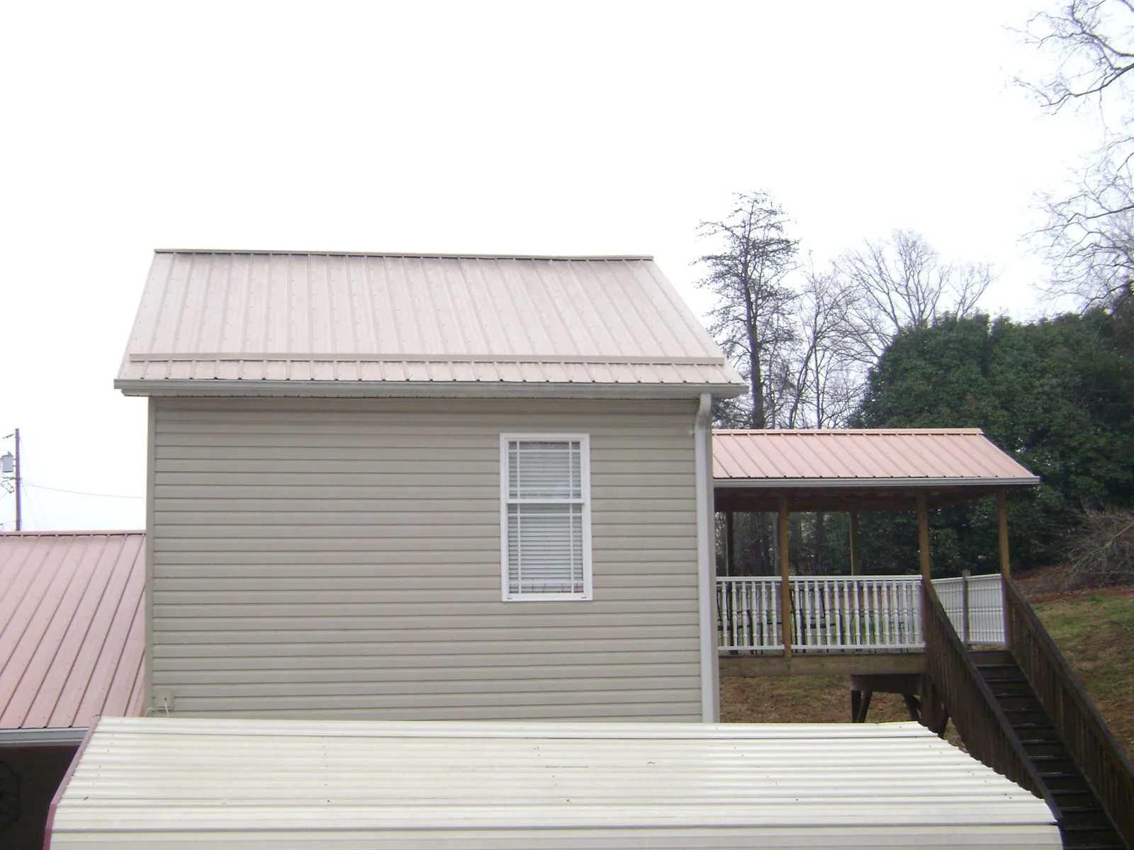 Tan metal roofs on a two story addition and attached porch, from a Roof Replacement job in Kingman